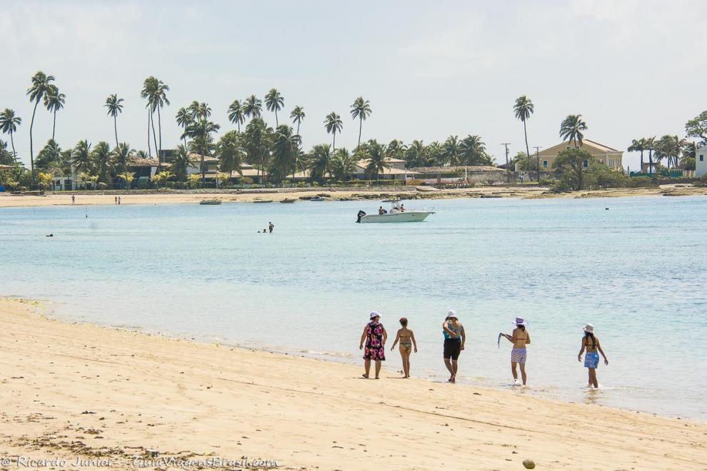 Imagem de amigas caminhando na orla da praia na Ilha de Itaparica.